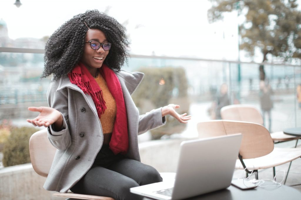 A woman in a coat on a video call, on her laptop, outside.